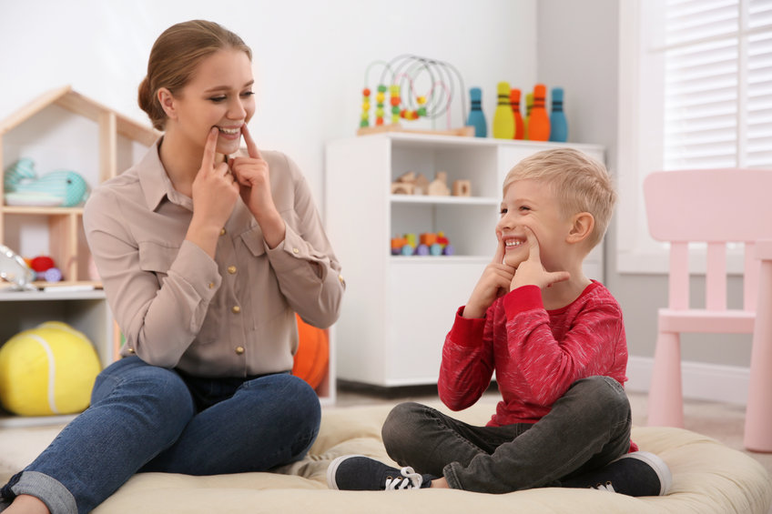 Speech therapist working with little boy in office